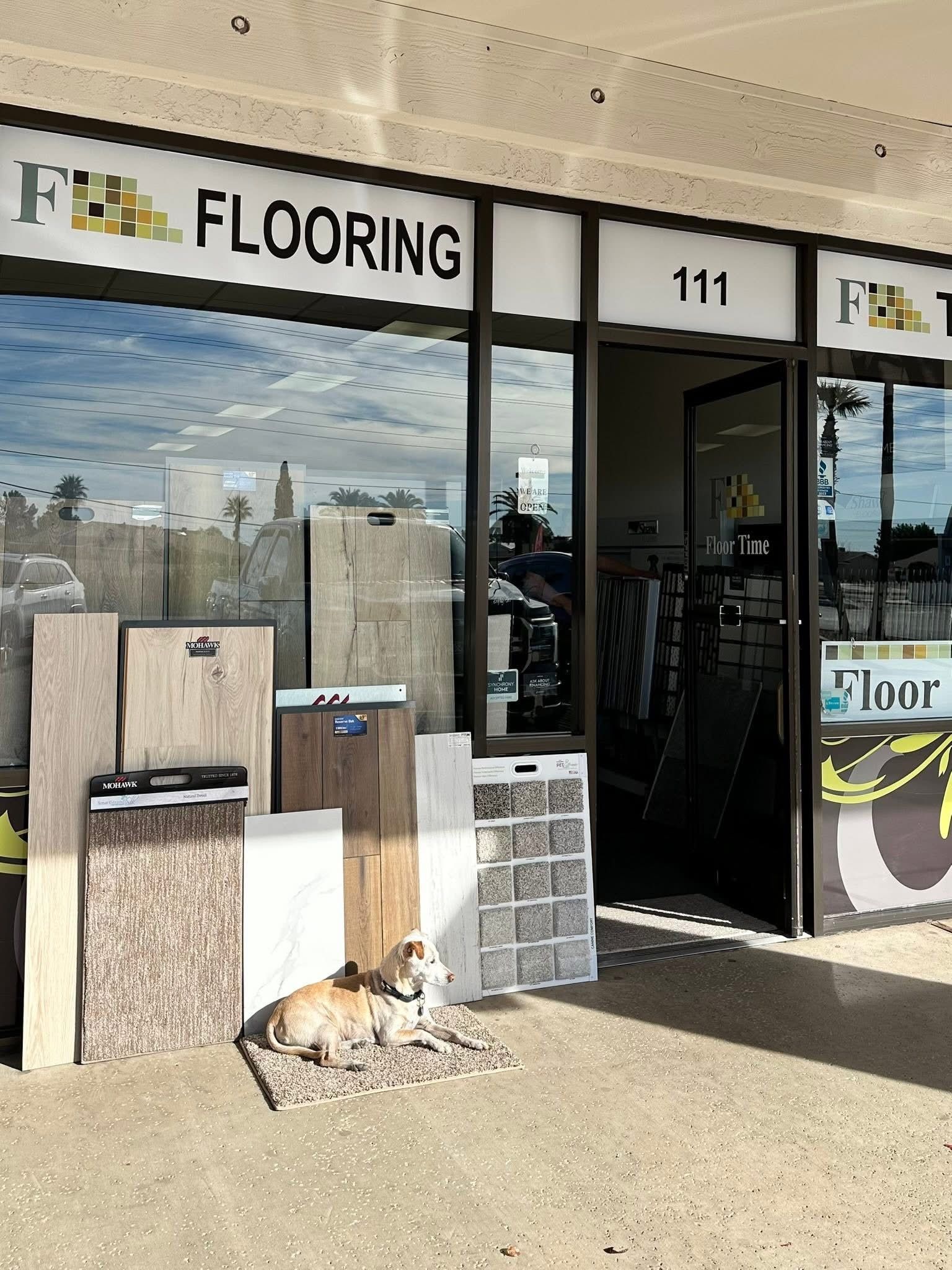 Flooring store storefront with sample displays and a dog lying outside near the entrance