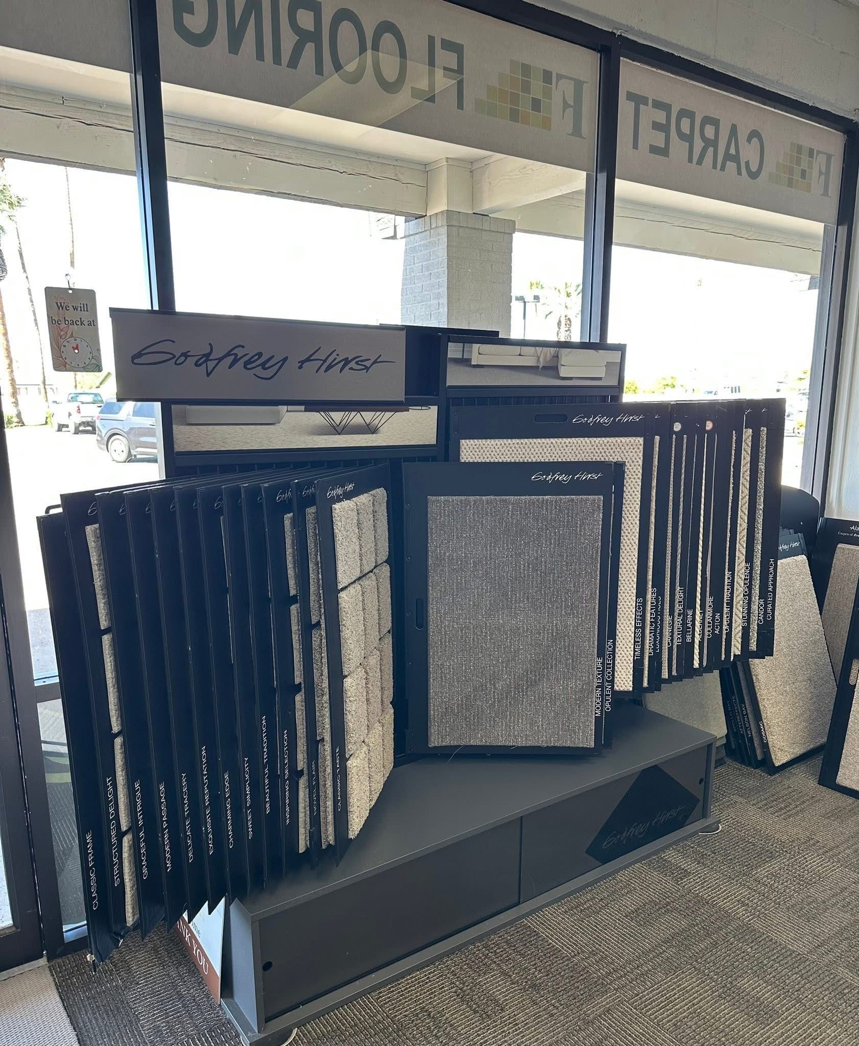 Storefront display of framed wall art and rugs arranged in a showroom window