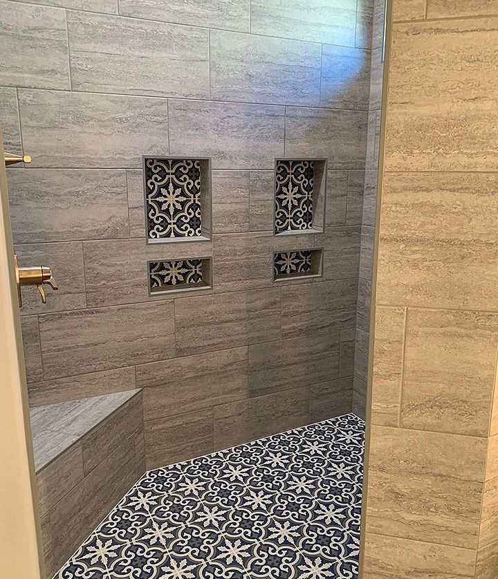 Stone shower with patterned black-and-white tile niches and floor