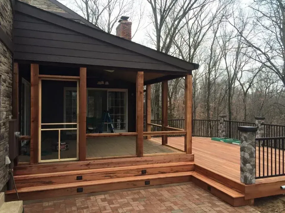 Wooden cabin porch with steps and railing, set among bare trees on a wooded lot