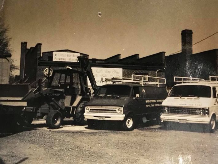 A black and white photo of several vehicles parked in front of a building