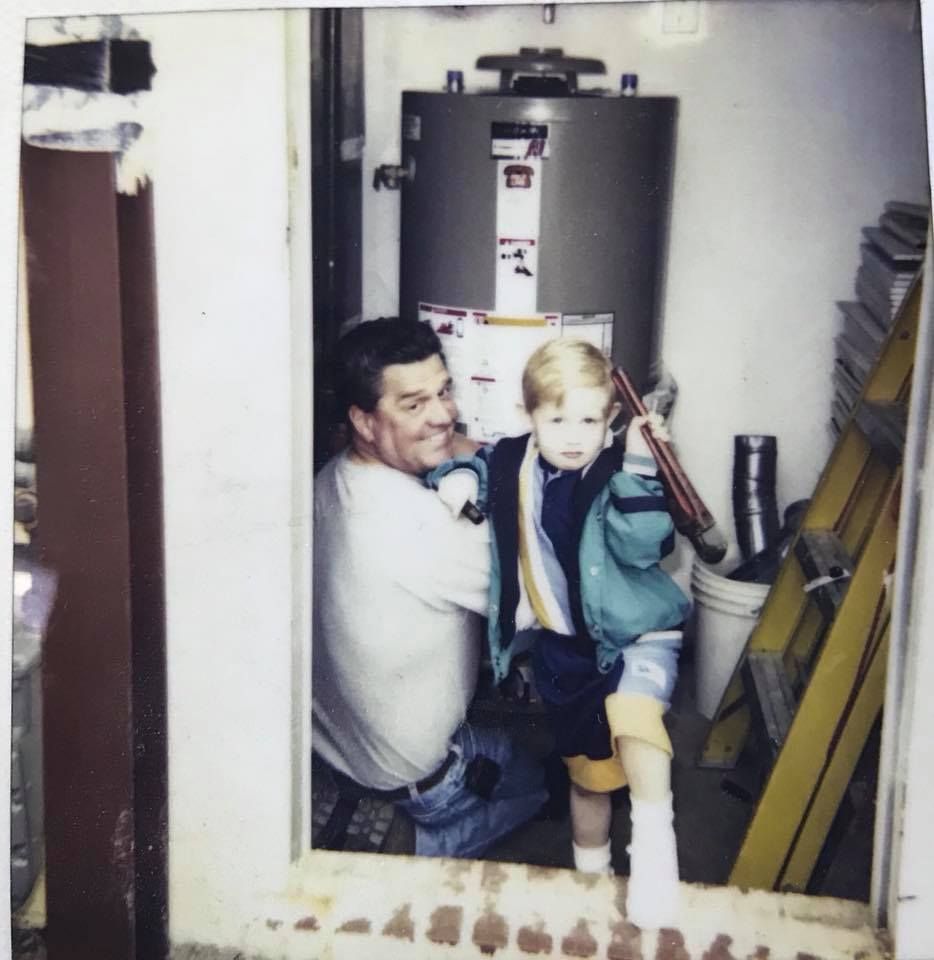 A man kneeling down with a child in front of a water heater