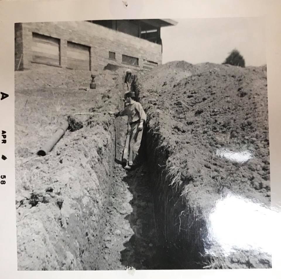 A black and white photo of a man digging in the dirt