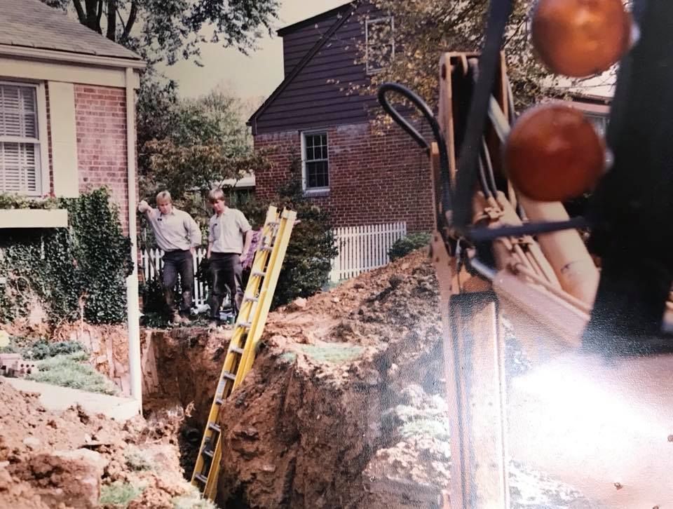 A black and white photo of a construction site with a house in the background