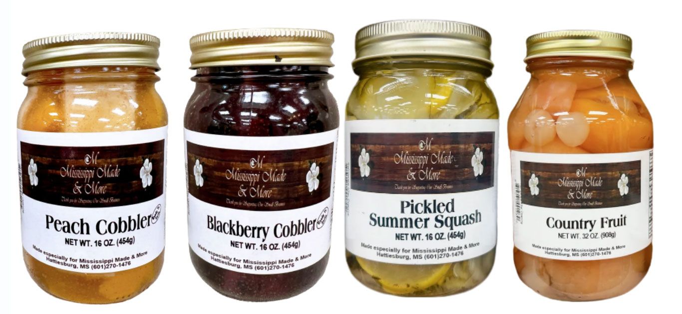 Four labeled jars of homemade preserves: Peach Cobbler, Blackberry Cobbler, Pickled Summer Squash, and Country Fruit.