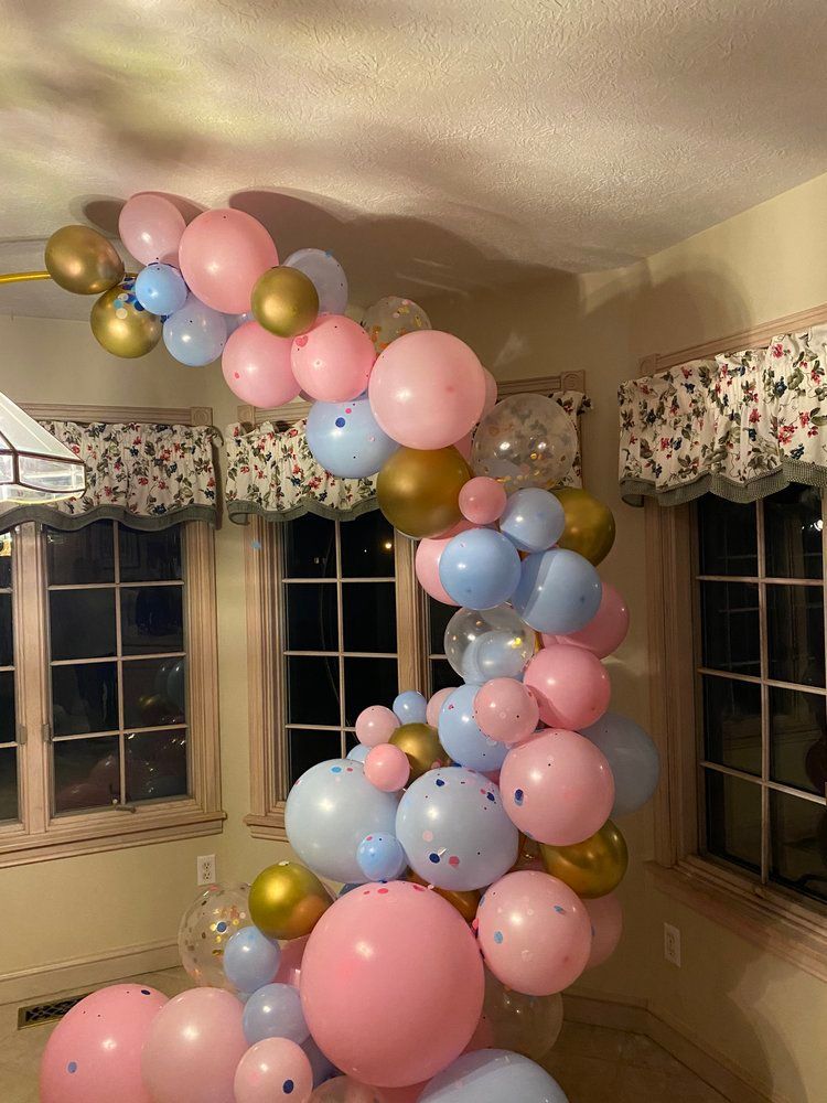 A room filled with pink , blue , and gold balloons.