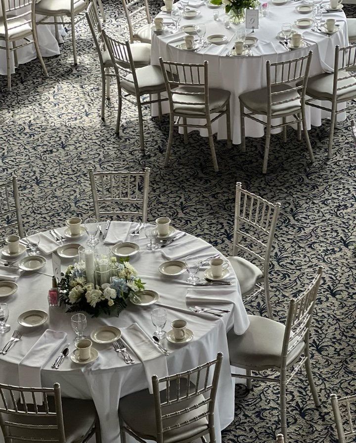 A large room with tables and chairs set up for a wedding reception
