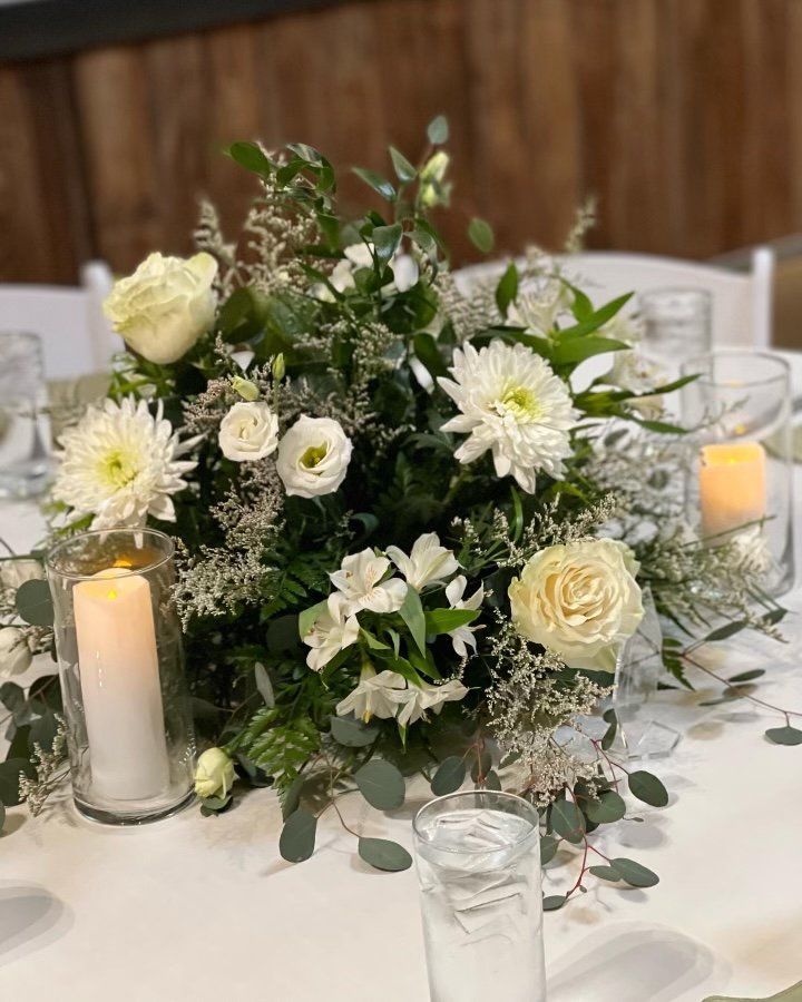A table with white flowers and candles on it.