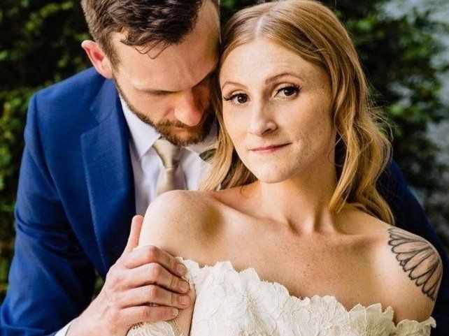 A man in a blue suit and tie is hugging a woman in a white dress.