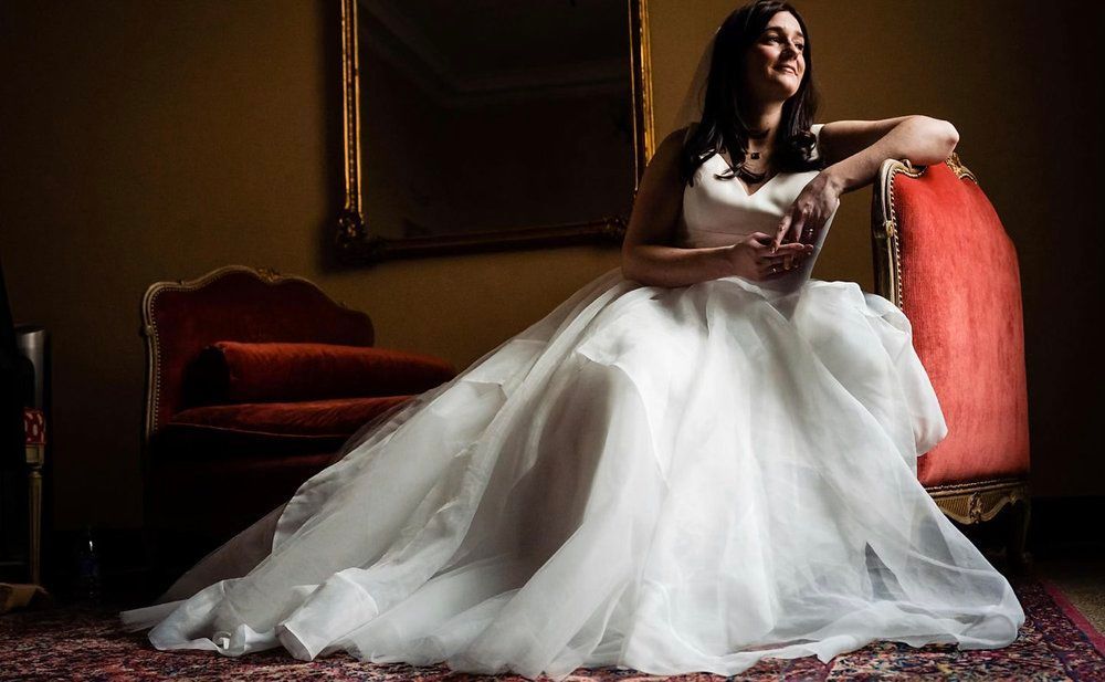 A woman in a wedding dress is sitting on a red couch.