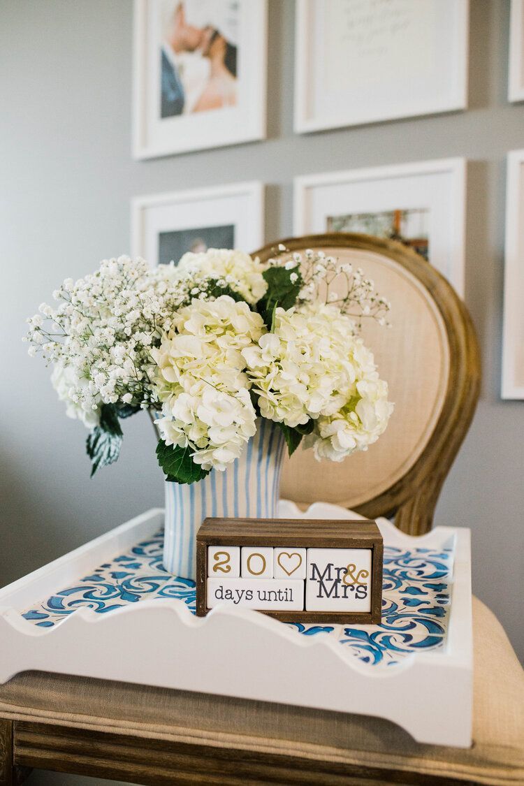 A vase of white flowers is sitting on a table next to a chair.