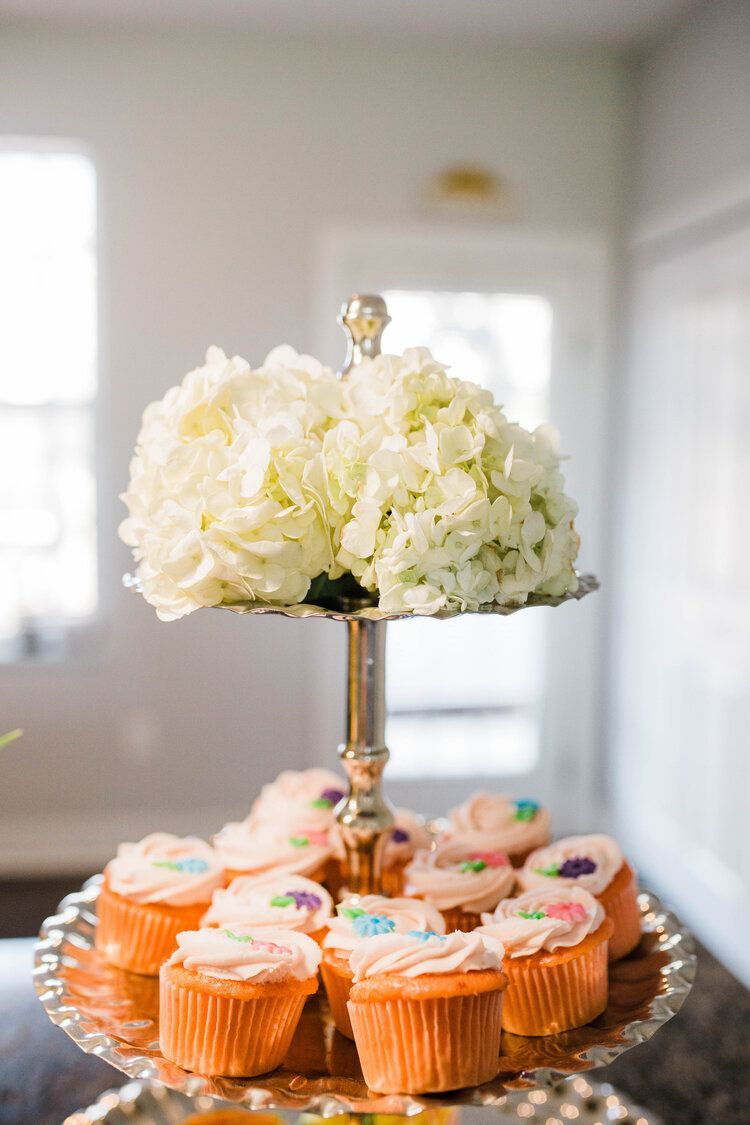 A cake stand filled with cupcakes and flowers on a table.