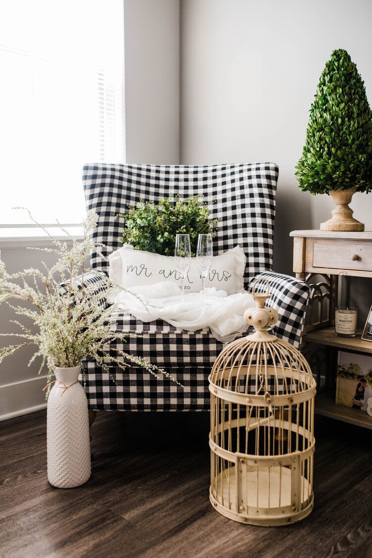 A black and white checkered chair is sitting next to a bird cage in a living room.