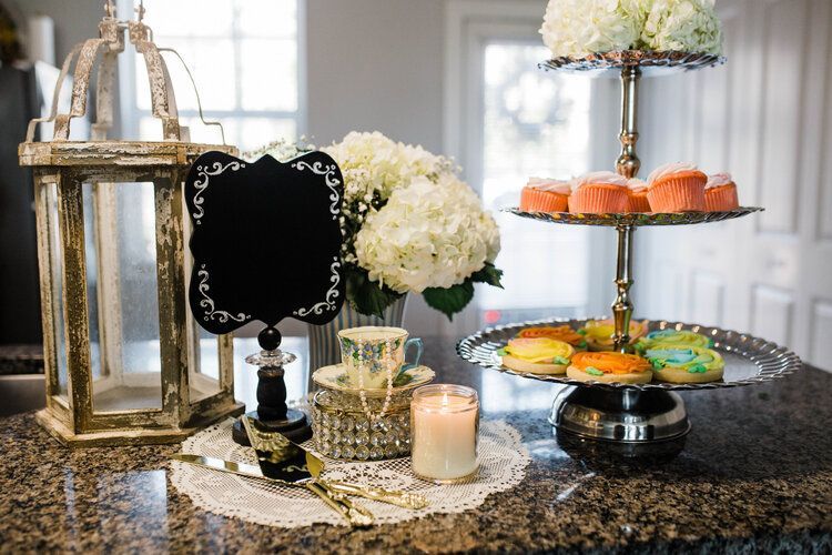 A table topped with a tray of cookies , a candle , flowers and a lantern.