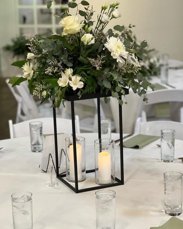 A table with a lantern filled with flowers and candles.