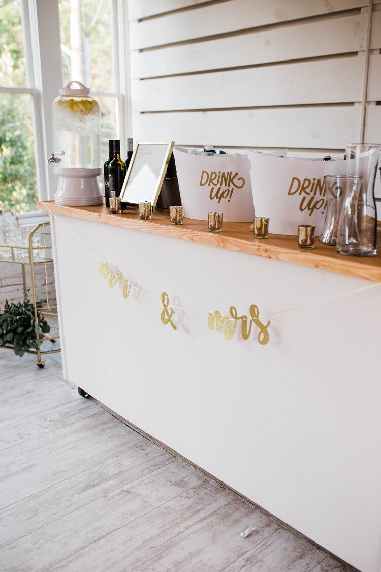 A white bar with a wooden counter top and buckets on it.