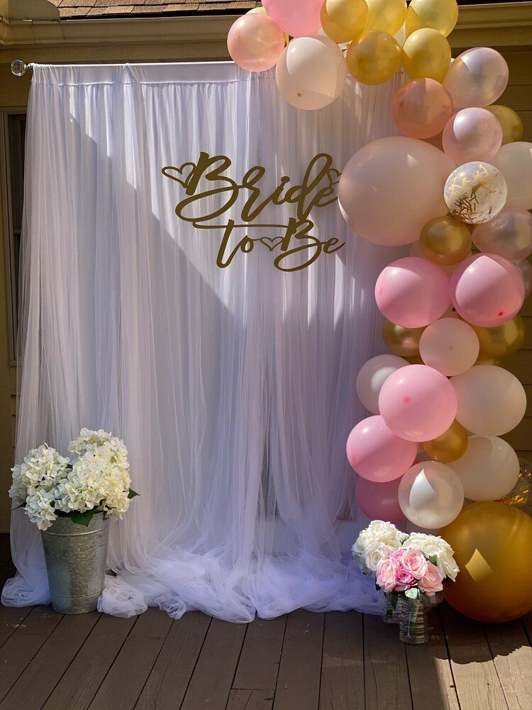 A bride to be backdrop with pink and gold balloons and flowers.