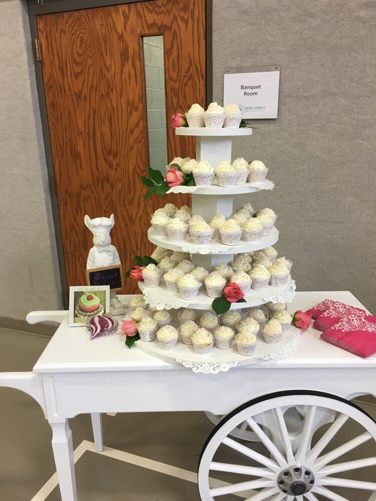 A cupcake tower is sitting on top of a white cart.