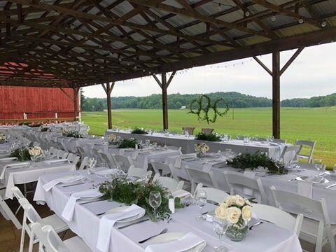 A covered area with tables and chairs set up for a wedding reception.