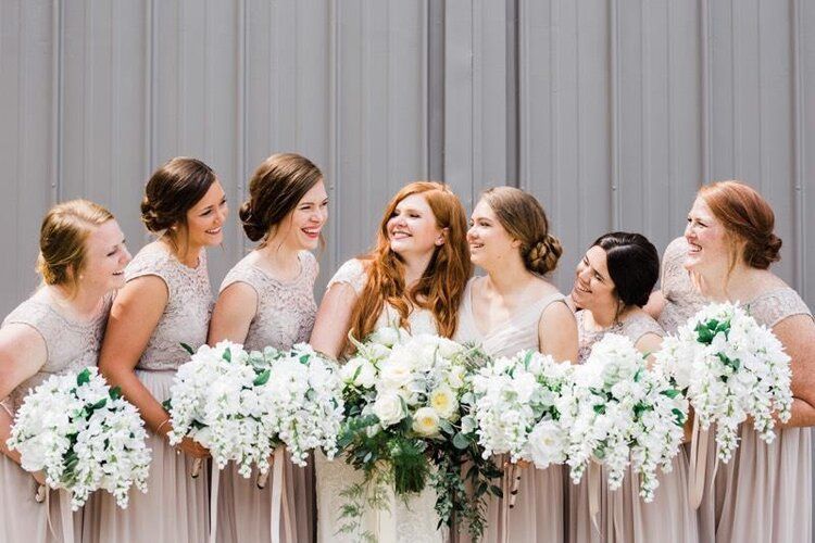 A bride and her bridesmaids are posing for a picture together.