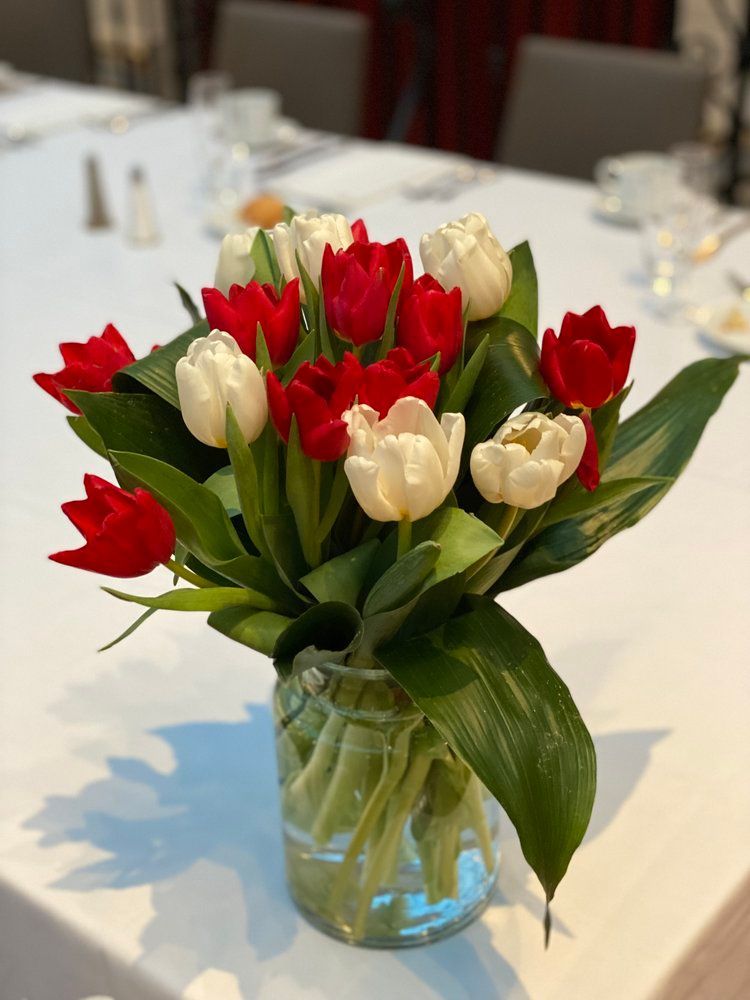 A vase filled with red and white tulips on a table.