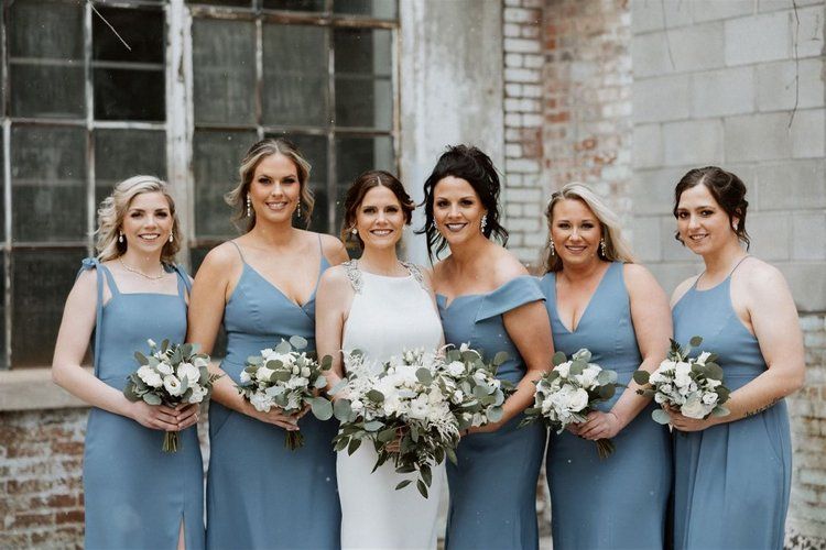 A bride and her bridesmaids are posing for a picture.
