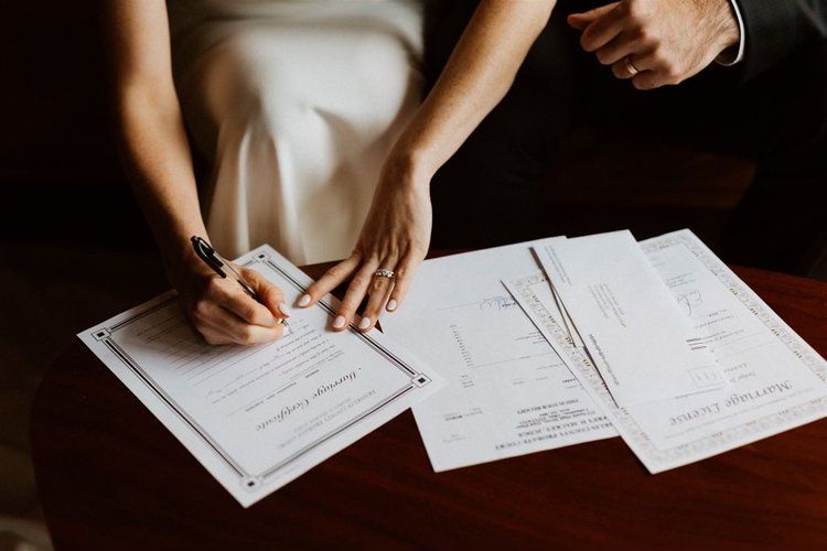 A bride and groom are signing a wedding certificate.