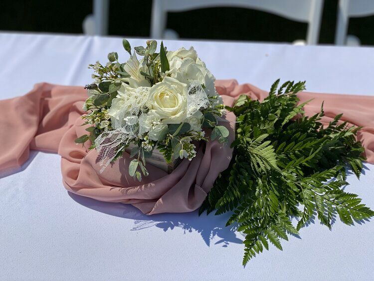 A table with a bouquet of flowers and ferns on it.