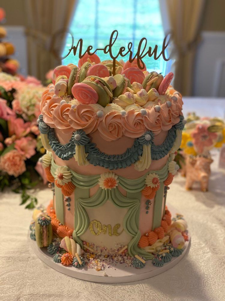 A cake with flowers and macarons on it is sitting on a table.