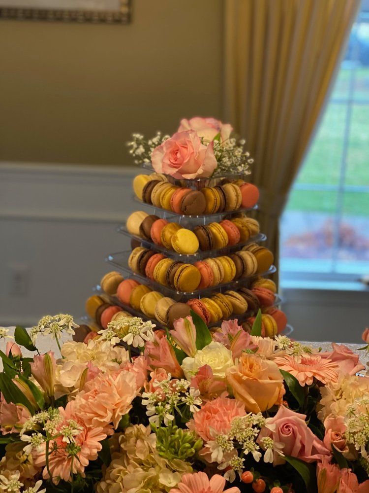 A stack of macarons sitting on top of a table surrounded by flowers.