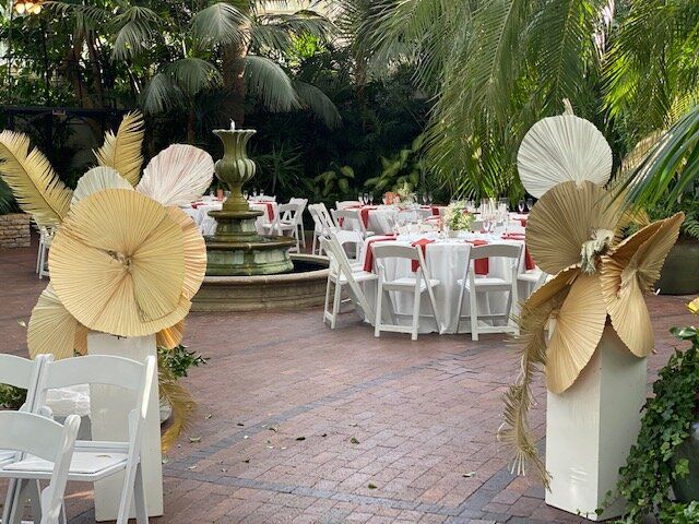 A patio with tables and chairs and a fountain in the background