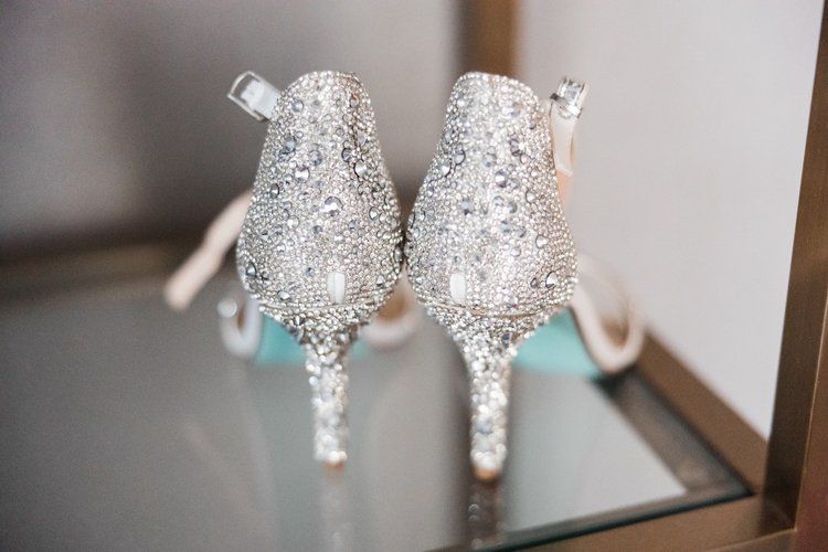 A pair of wedding shoes are sitting on a glass shelf.