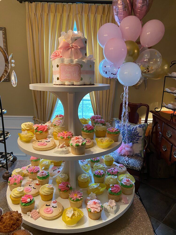 A cupcake stand filled with cupcakes and balloons for a baby shower.