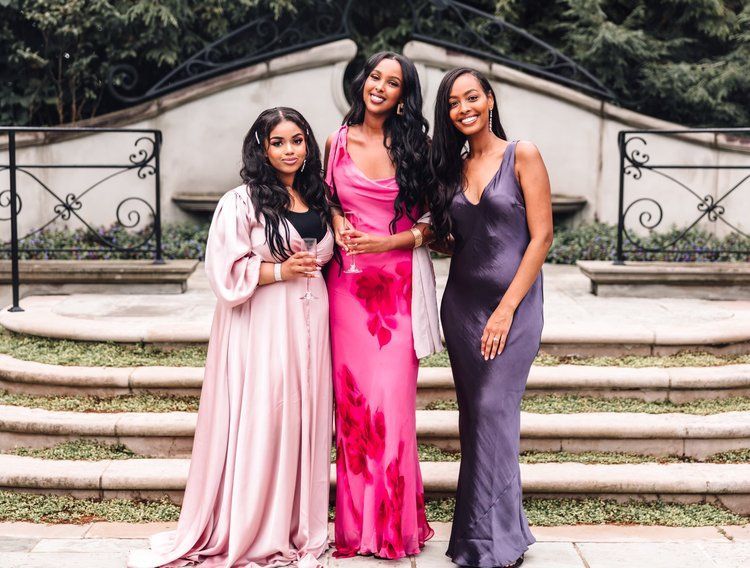 Three women in long dresses are posing for a picture.