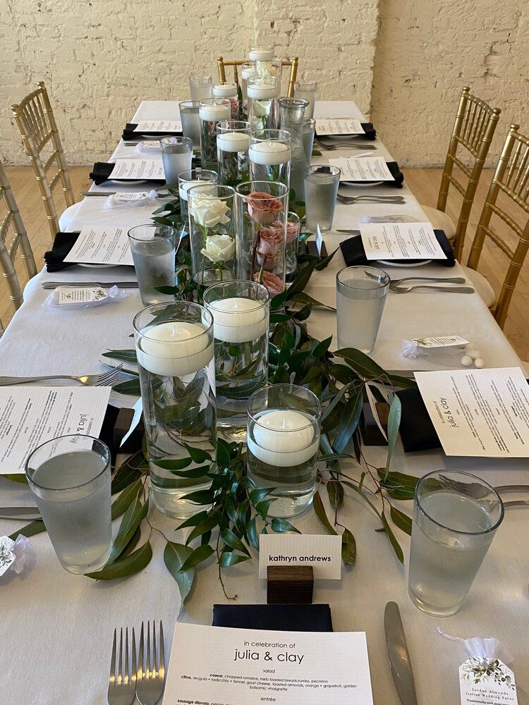 A long table set for a wedding reception with candles in glasses.