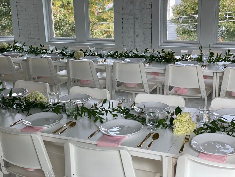 A long table with plates , utensils , and flowers on it.