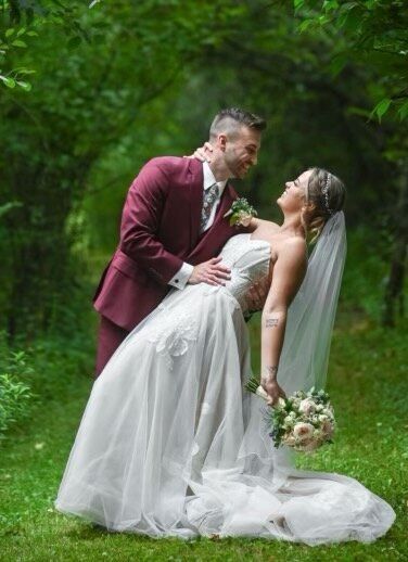 A bride and groom are posing for a picture in the woods.