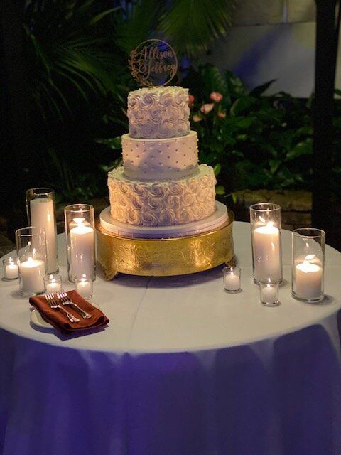 A wedding cake is on a table with candles