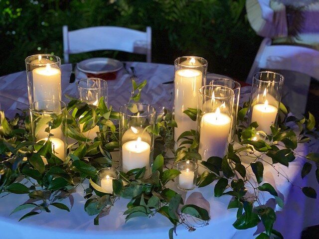 A table with candles and greenery on it.