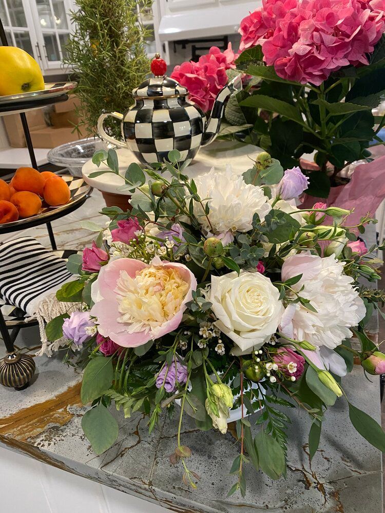 A bouquet of flowers is sitting on a table next to a checkered teapot.