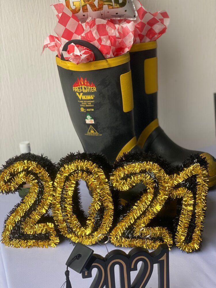 A pair of black and yellow fire boots are sitting on a table next to a sign that says 2021