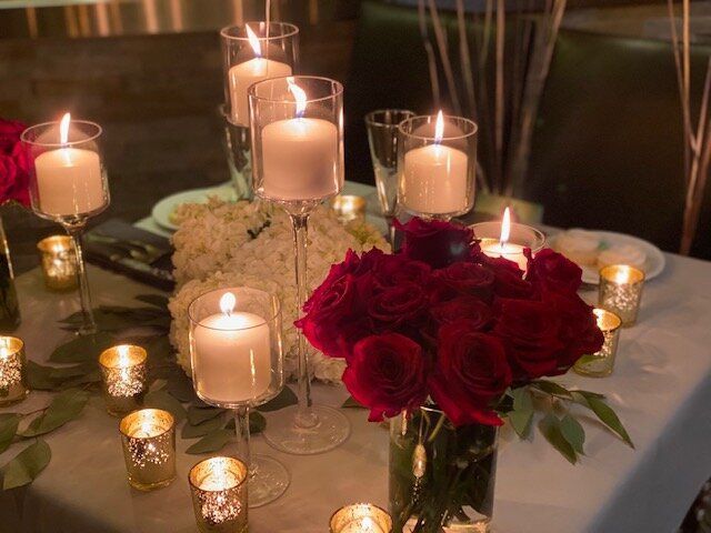 A table with candles and red roses on it.
