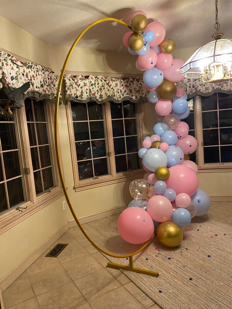 A room filled with pink , blue , and gold balloons.