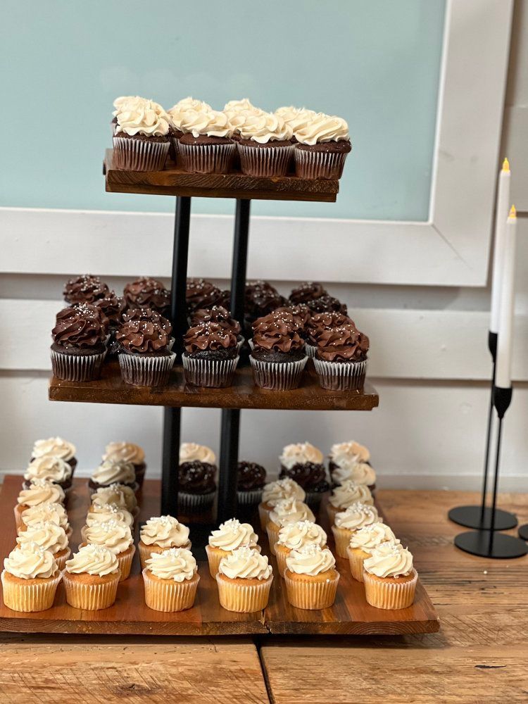 A wooden cupcake holder filled with cupcakes on a wooden table.