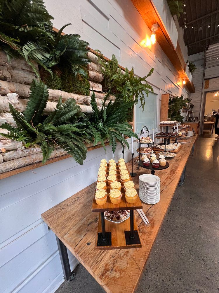 A long wooden table with cupcakes on it in a room.