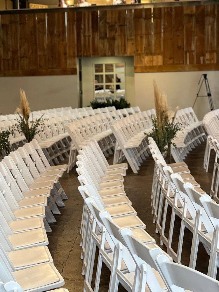 Rows of white folding chairs are lined up in a room.