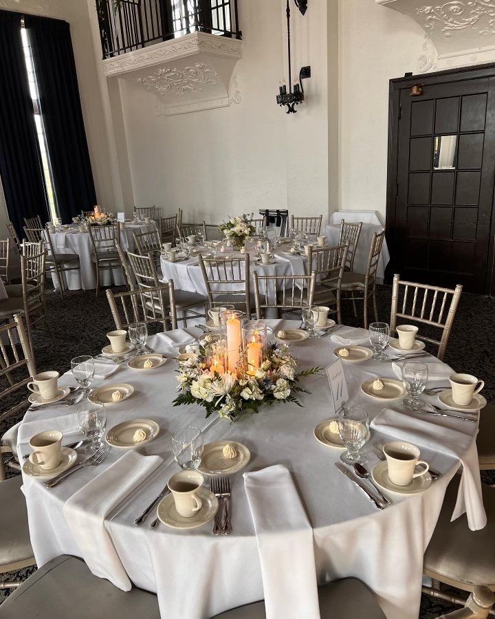 A large room with tables and chairs set up for a wedding reception.