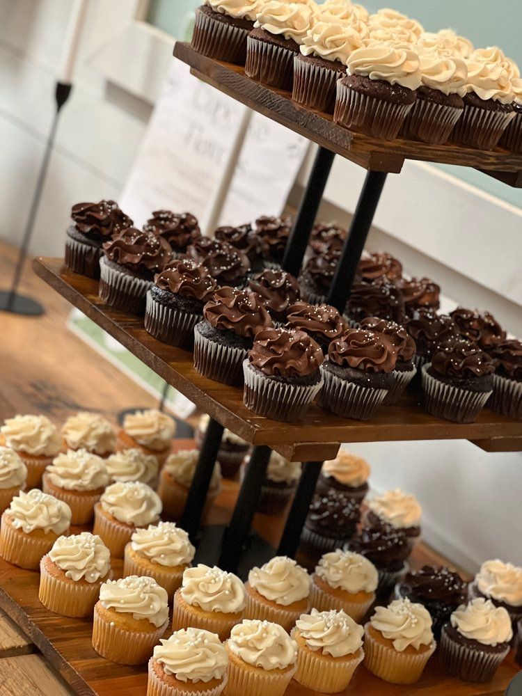 A wooden cupcake tower filled with lots of different cupcakes.