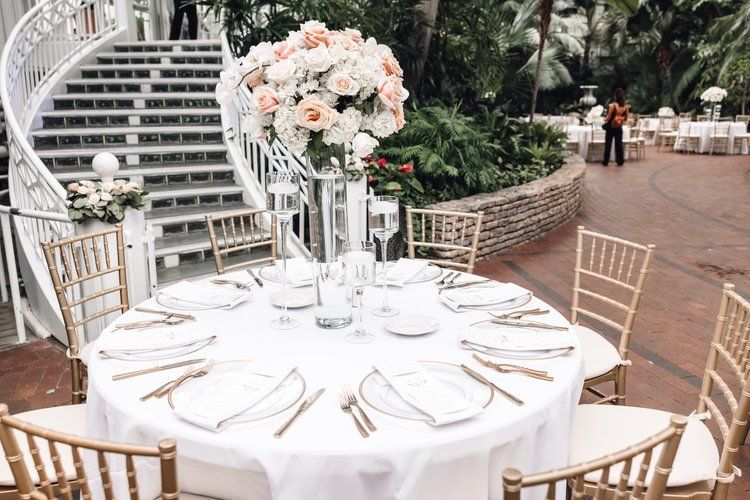 A table set for a wedding reception with a vase of flowers on it.