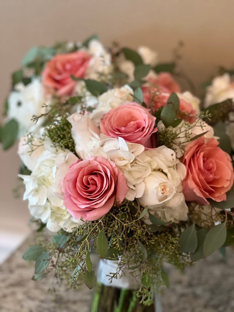 A bouquet of pink and white roses and hydrangeas is sitting on a table.